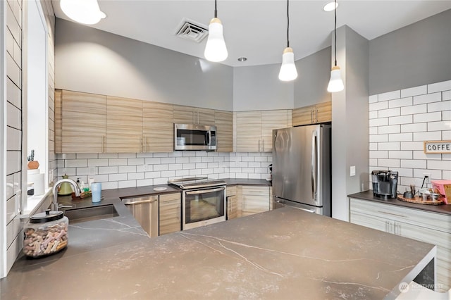 kitchen with pendant lighting, appliances with stainless steel finishes, sink, and stainless steel counters