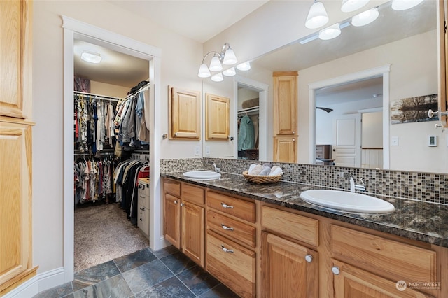 bathroom with tasteful backsplash, stone finish flooring, a sink, and double vanity