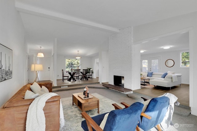 living room featuring french doors, a fireplace, and lofted ceiling with beams