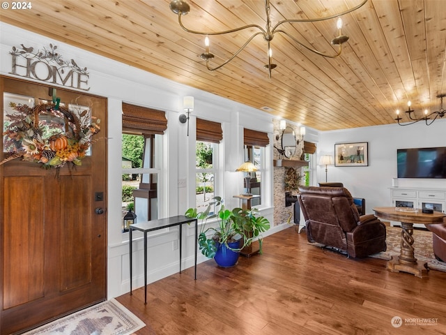 foyer featuring wood-type flooring, a fireplace, and a chandelier