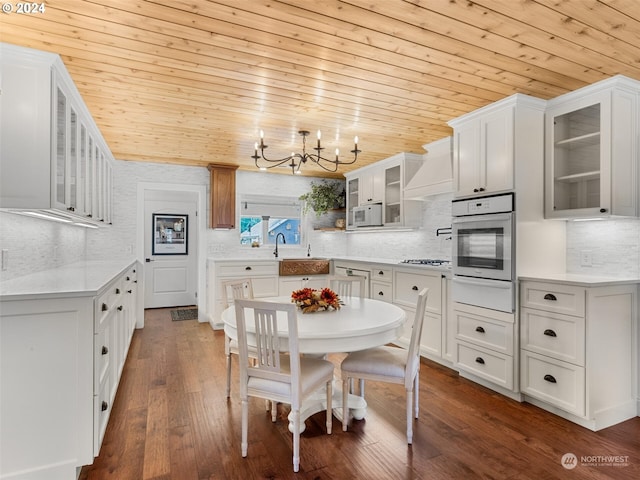 kitchen with white appliances, dark hardwood / wood-style floors, white cabinets, custom exhaust hood, and wooden ceiling