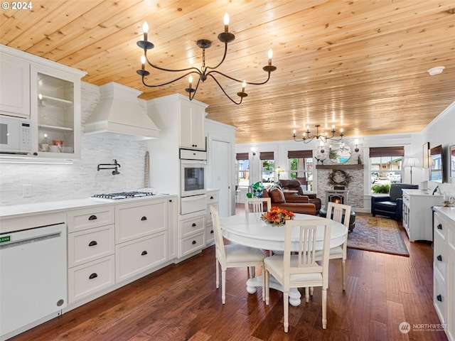 dining area with dark hardwood / wood-style flooring, a stone fireplace, wooden ceiling, and a chandelier