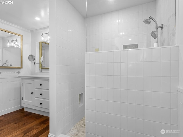 bathroom featuring hardwood / wood-style flooring, vanity, tiled shower, and crown molding