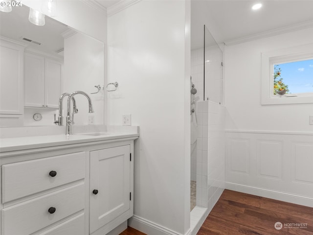 bathroom with hardwood / wood-style flooring, crown molding, a tile shower, and vanity