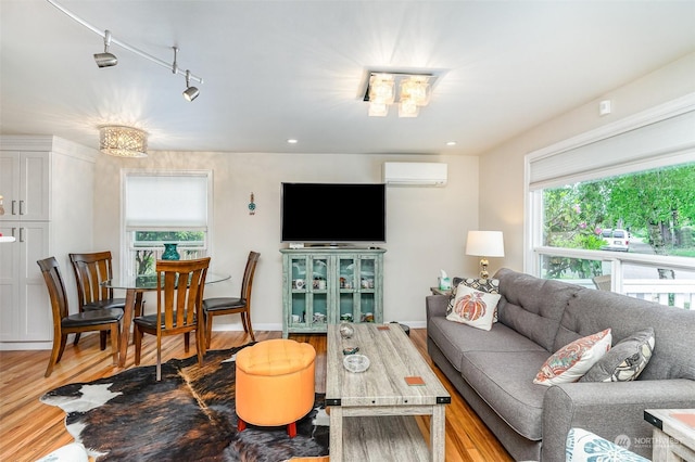 living room with rail lighting, a wall mounted air conditioner, and light hardwood / wood-style floors