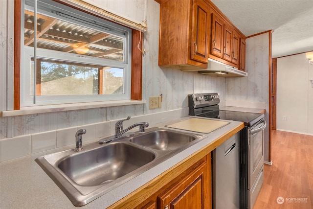 kitchen featuring appliances with stainless steel finishes, sink, a textured ceiling, and light hardwood / wood-style flooring