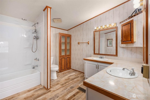 full bathroom with toilet, wood-type flooring, shower / bathtub combination, ornamental molding, and vanity