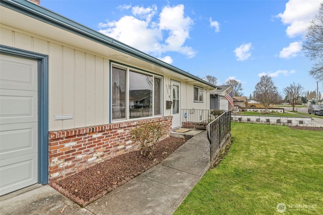 view of side of property with a garage, brick siding, and a yard