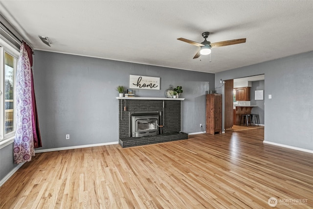 unfurnished living room featuring light wood-style floors, ceiling fan, a textured ceiling, and baseboards