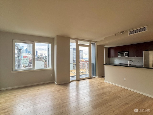 unfurnished living room featuring sink and light hardwood / wood-style floors