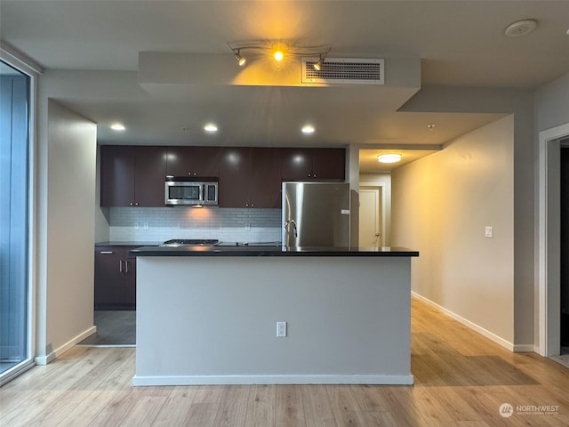 kitchen featuring decorative backsplash, stainless steel appliances, an island with sink, and dark brown cabinets