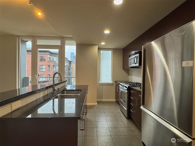 kitchen with sink, backsplash, a center island, light tile patterned floors, and stainless steel appliances