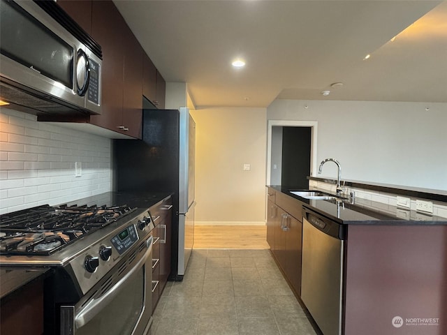 kitchen with sink, tasteful backsplash, dark brown cabinets, dark stone countertops, and appliances with stainless steel finishes