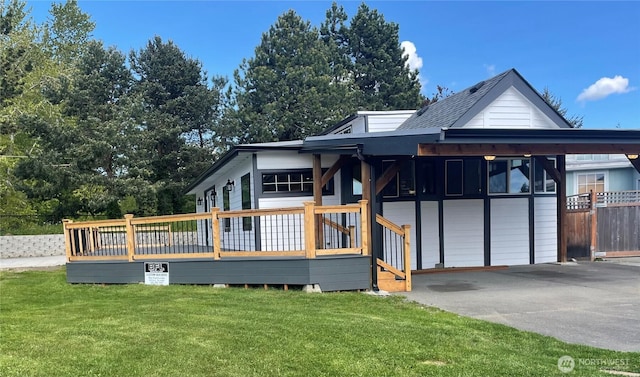 view of front of home with a garage, fence, a deck, aphalt driveway, and a front lawn