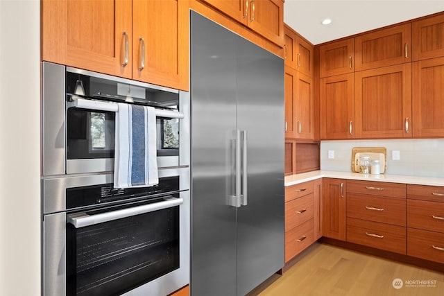 kitchen featuring stainless steel appliances, light hardwood / wood-style flooring, and backsplash