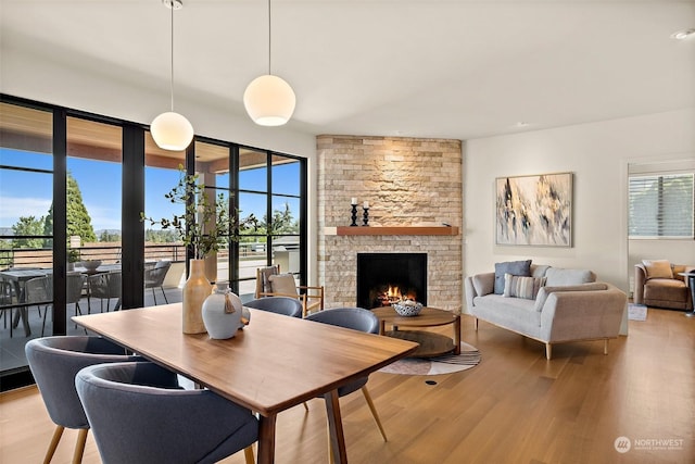 dining area featuring a stone fireplace, plenty of natural light, and light hardwood / wood-style flooring