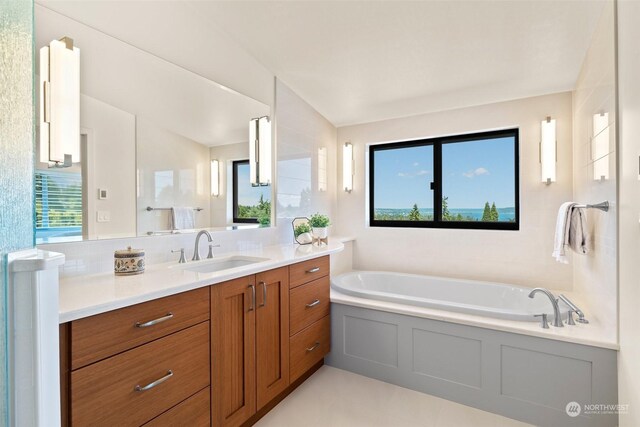 bathroom with tasteful backsplash, vanity, a bath, and vaulted ceiling