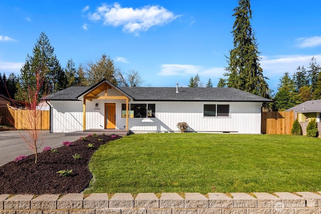 view of front facade with a front lawn, fence, roof with shingles, and crawl space