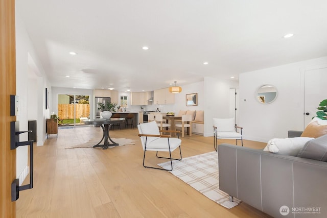 living area featuring recessed lighting, baseboards, and light wood finished floors