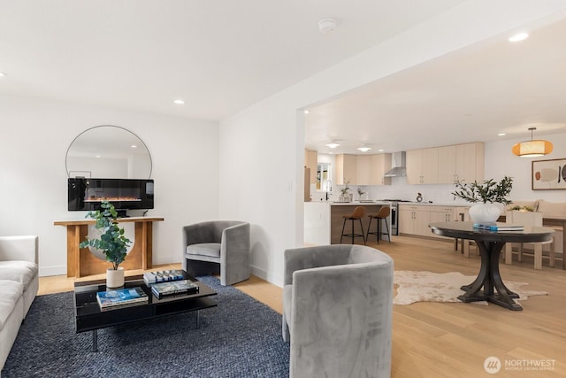 living area with recessed lighting, baseboards, and light wood finished floors