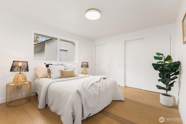 bedroom with multiple closets and wood finished floors