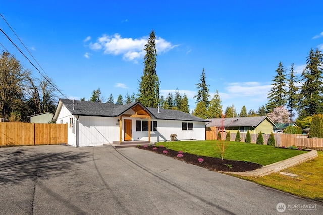 view of front of house featuring driveway, a front yard, and fence