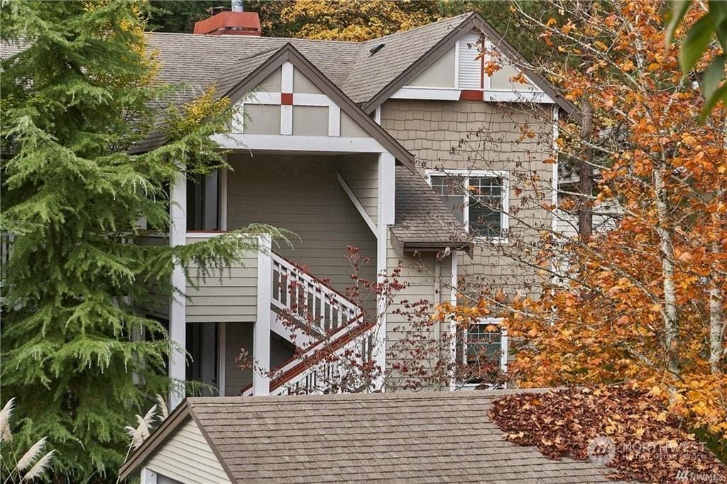 view of front of home featuring stairway, roof with shingles, and a chimney