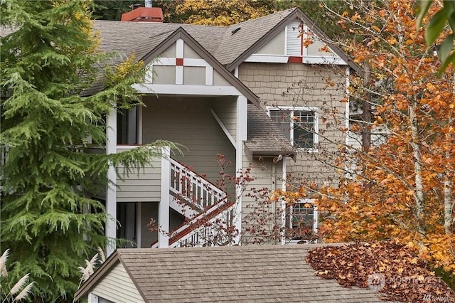 view of front of home featuring stairway, roof with shingles, and a chimney