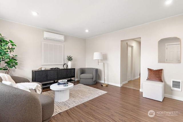 living room featuring hardwood / wood-style flooring, ornamental molding, and an AC wall unit