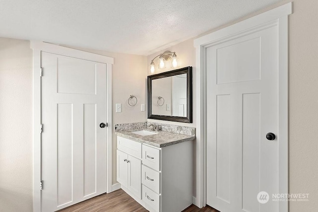 bathroom with hardwood / wood-style flooring, vanity, and a textured ceiling