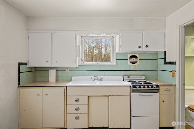 kitchen with tasteful backsplash, sink, white electric range oven, and white cabinets