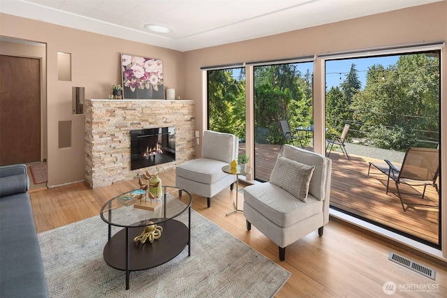 living room featuring a stone fireplace and light hardwood / wood-style floors