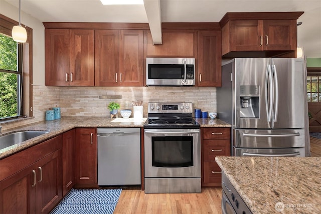 kitchen featuring stainless steel appliances, tasteful backsplash, light stone countertops, light hardwood / wood-style floors, and decorative light fixtures