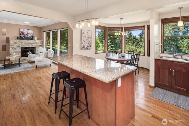 kitchen with light hardwood / wood-style floors, light stone countertops, sink, and a wealth of natural light