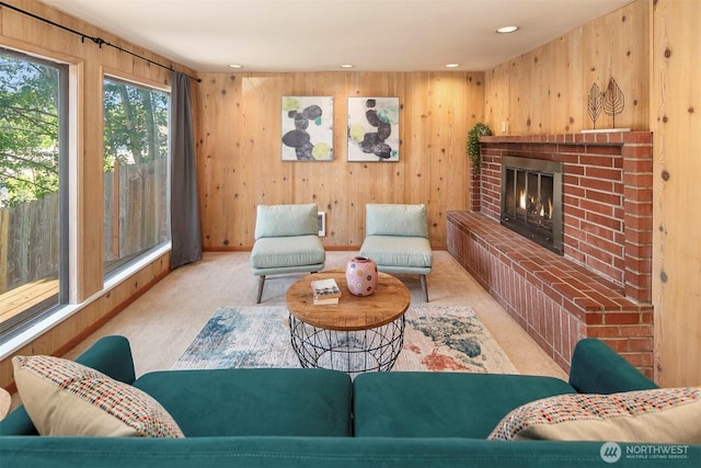 living room featuring light colored carpet, a fireplace, and wood walls