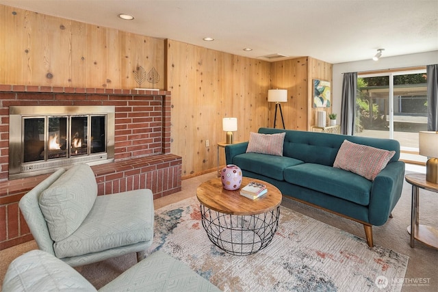 living room featuring wooden walls, a fireplace, and carpet flooring