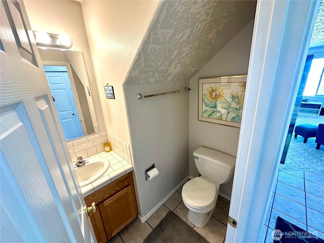 bathroom with toilet, vanity, baseboards, backsplash, and tile patterned floors