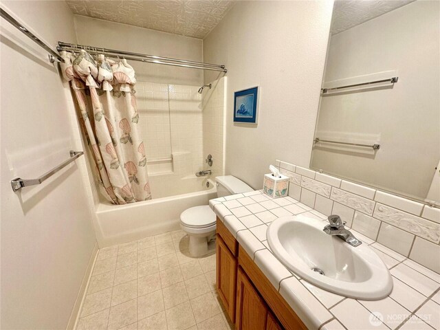 full bathroom with toilet, shower / bath combo with shower curtain, a textured ceiling, vanity, and baseboards