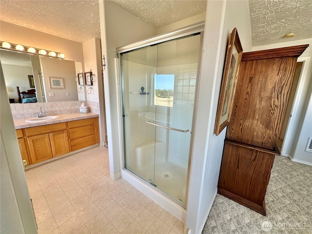 full bath with a shower stall, a textured ceiling, and vanity