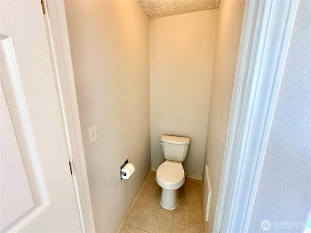 bathroom featuring toilet, baseboards, and tile patterned floors