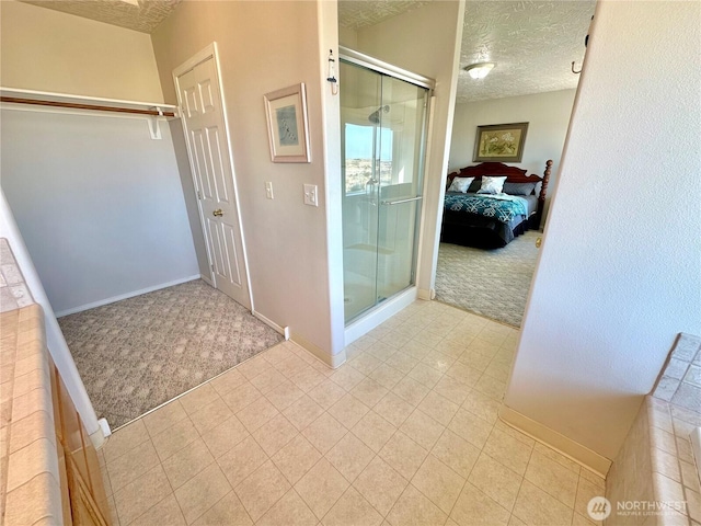 ensuite bathroom featuring baseboards, ensuite bath, a shower stall, and a textured ceiling