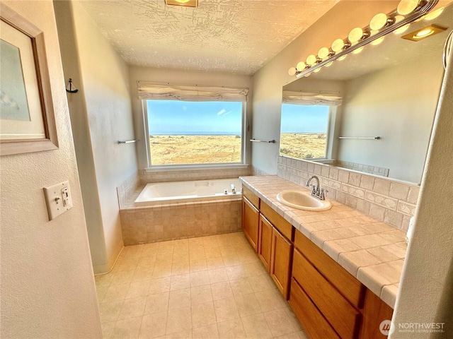 full bathroom with a garden tub, decorative backsplash, a textured ceiling, and vanity