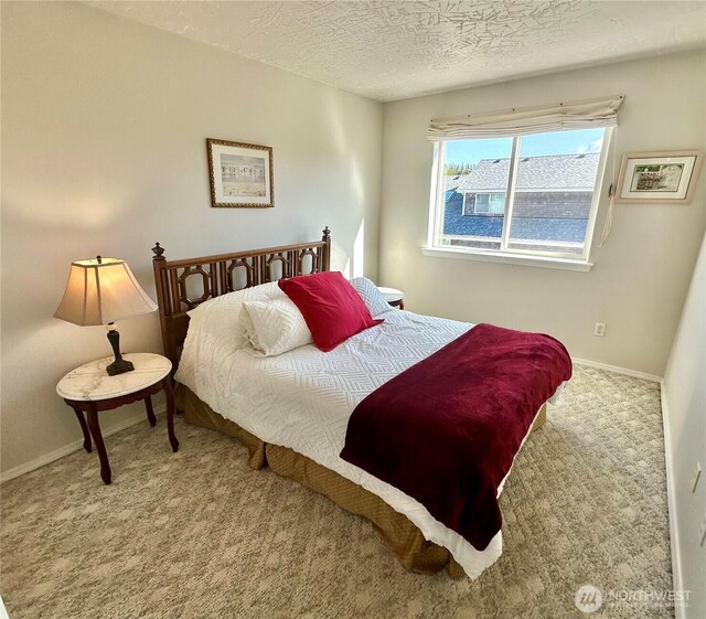 bedroom with carpet flooring, a textured ceiling, and baseboards