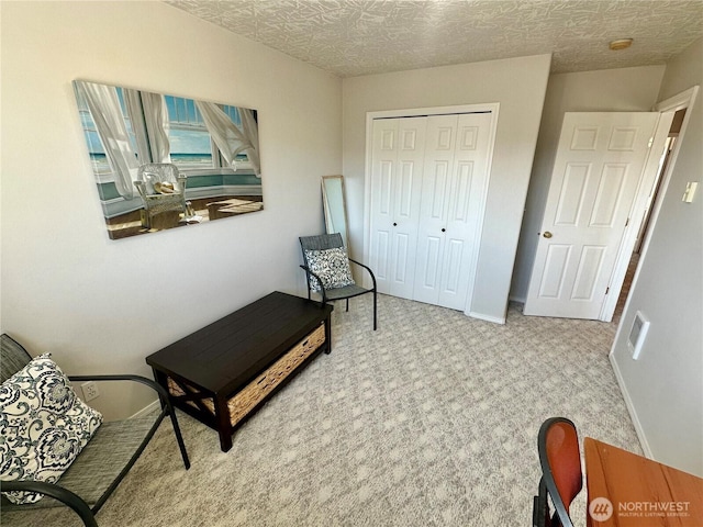 living area with carpet, a textured ceiling, and baseboards