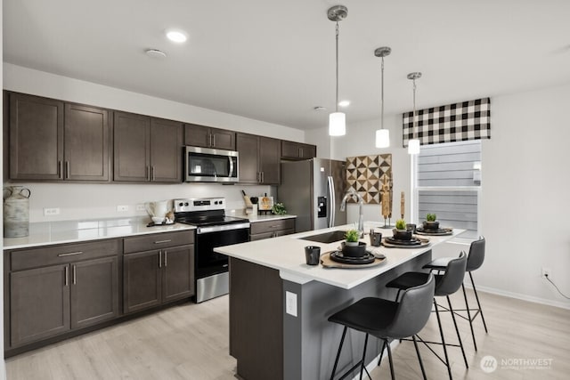 289 Wind River Ct, Chehalis, WA 98532 - kitchen featuring pendant lighting, appliances with stainless steel finishes, a kitchen breakfast bar, light hardwood / wood-style floors, and an island with sink