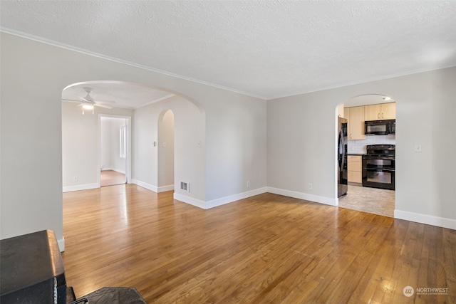 unfurnished living room with ceiling fan, ornamental molding, a textured ceiling, and light wood-type flooring