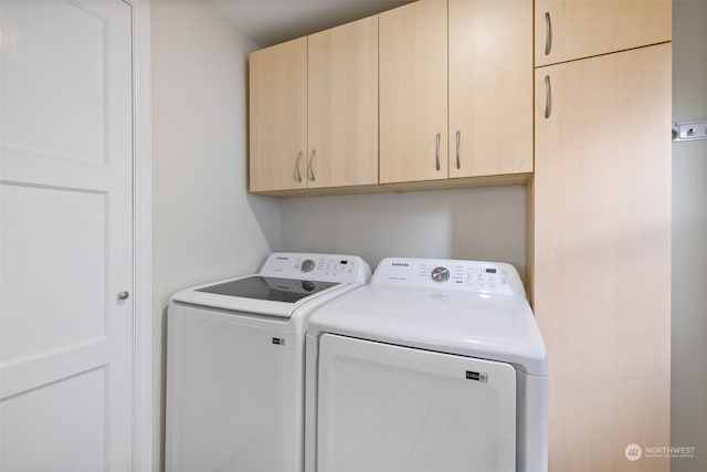 clothes washing area featuring cabinets and washing machine and dryer