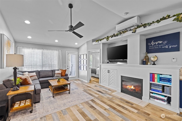 living room featuring ceiling fan, lofted ceiling, a wall unit AC, and light hardwood / wood-style flooring