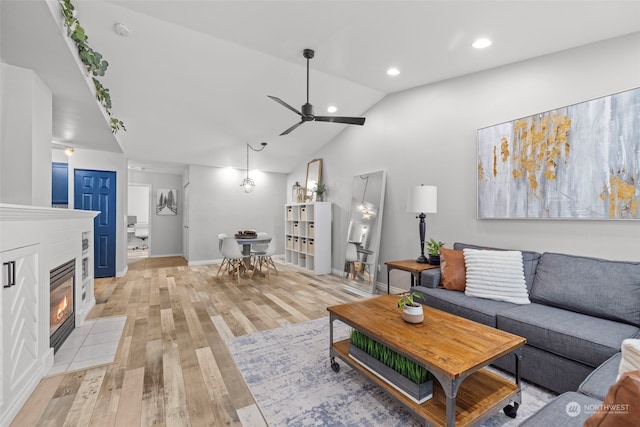 living room featuring ceiling fan, vaulted ceiling, and light hardwood / wood-style flooring