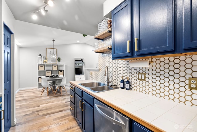 kitchen featuring blue cabinetry, sink, decorative light fixtures, stainless steel dishwasher, and tile counters